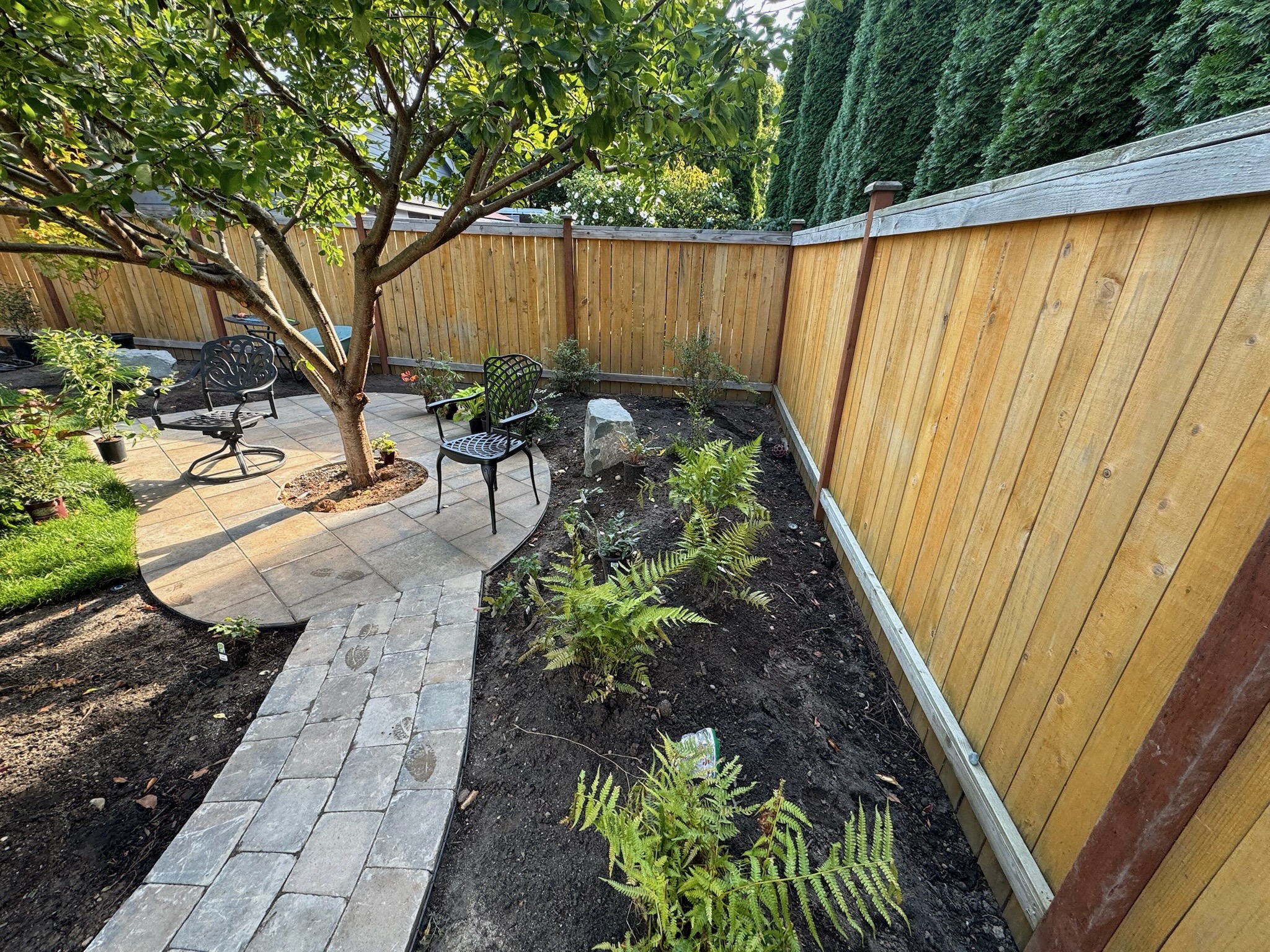 Patio with metal chairs, ferns, stone pathway at Todd's Nursery in Puyallup, WA