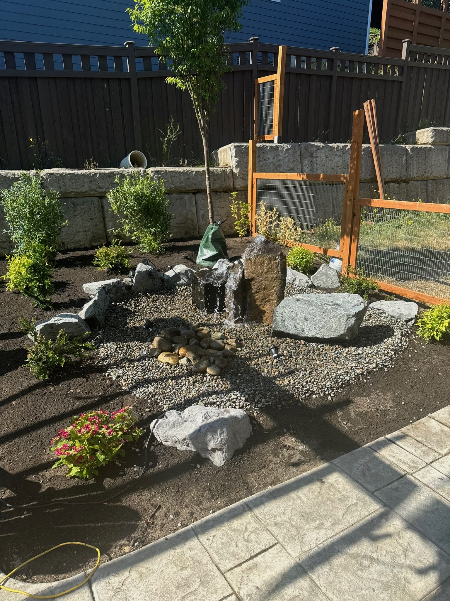 Garden with water feature, retaining wall, and plantings at Todd's Nursery in Puyallup, WA.