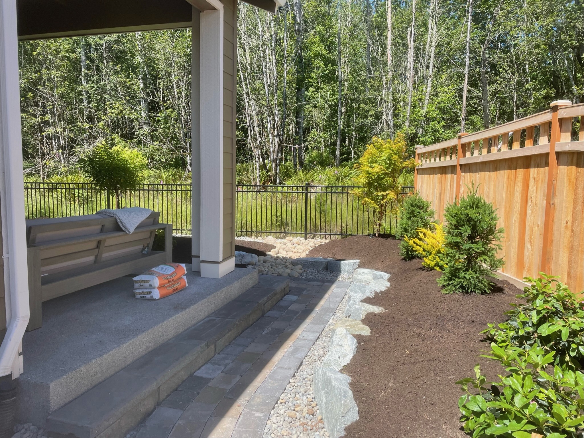 Patio with retaining wall, evergreens, and mulch by Todd's Nursery in Puyallup, WA
