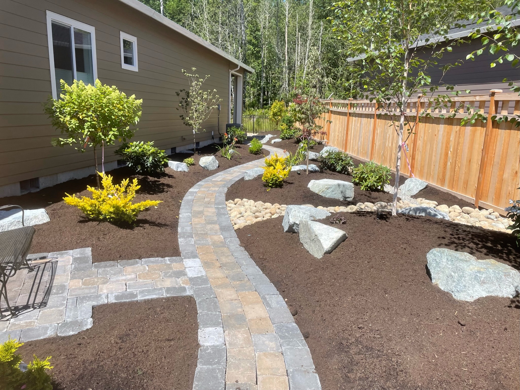 Landscaping by Todd's Nursery in Puyallup with stone path, shrubs, and mulch