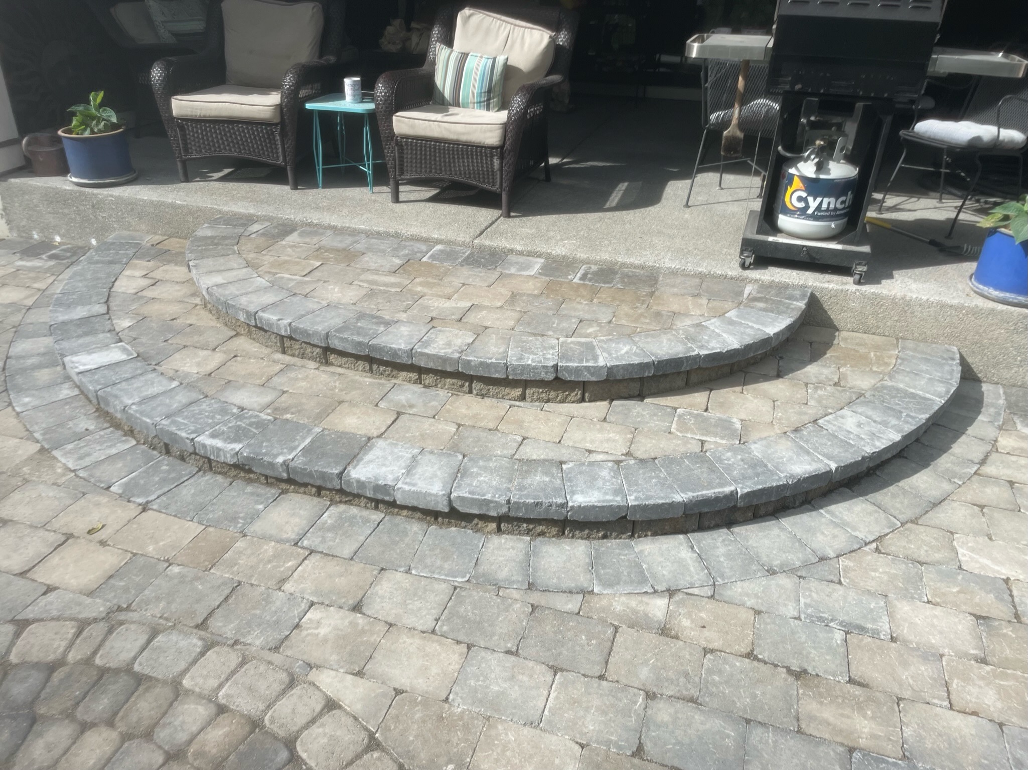 Stone patio with curved steps at Todd's Nursery in Puyallup, WA, featuring potted plants and outdoor seating.
