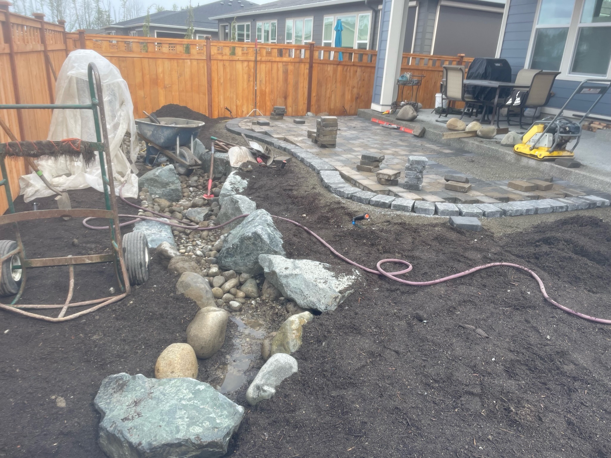 Landscaping project by Todd's Nursery in Puyallup, WA, featuring a stone patio, retaining wall, and water feature.