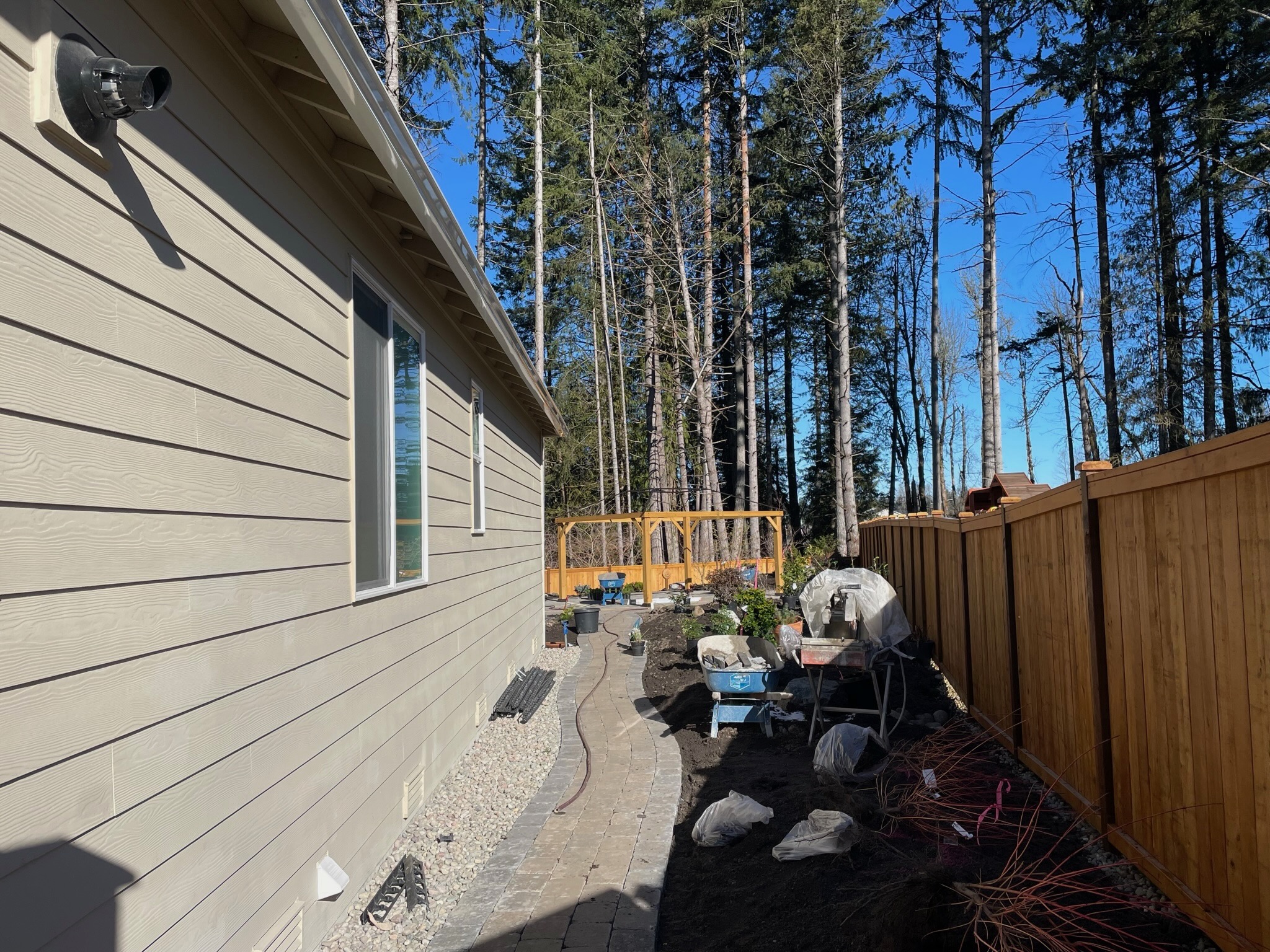 Todd's Nursery landscaping project in Puyallup featuring a paver pathway, wooden fence, and garden area.