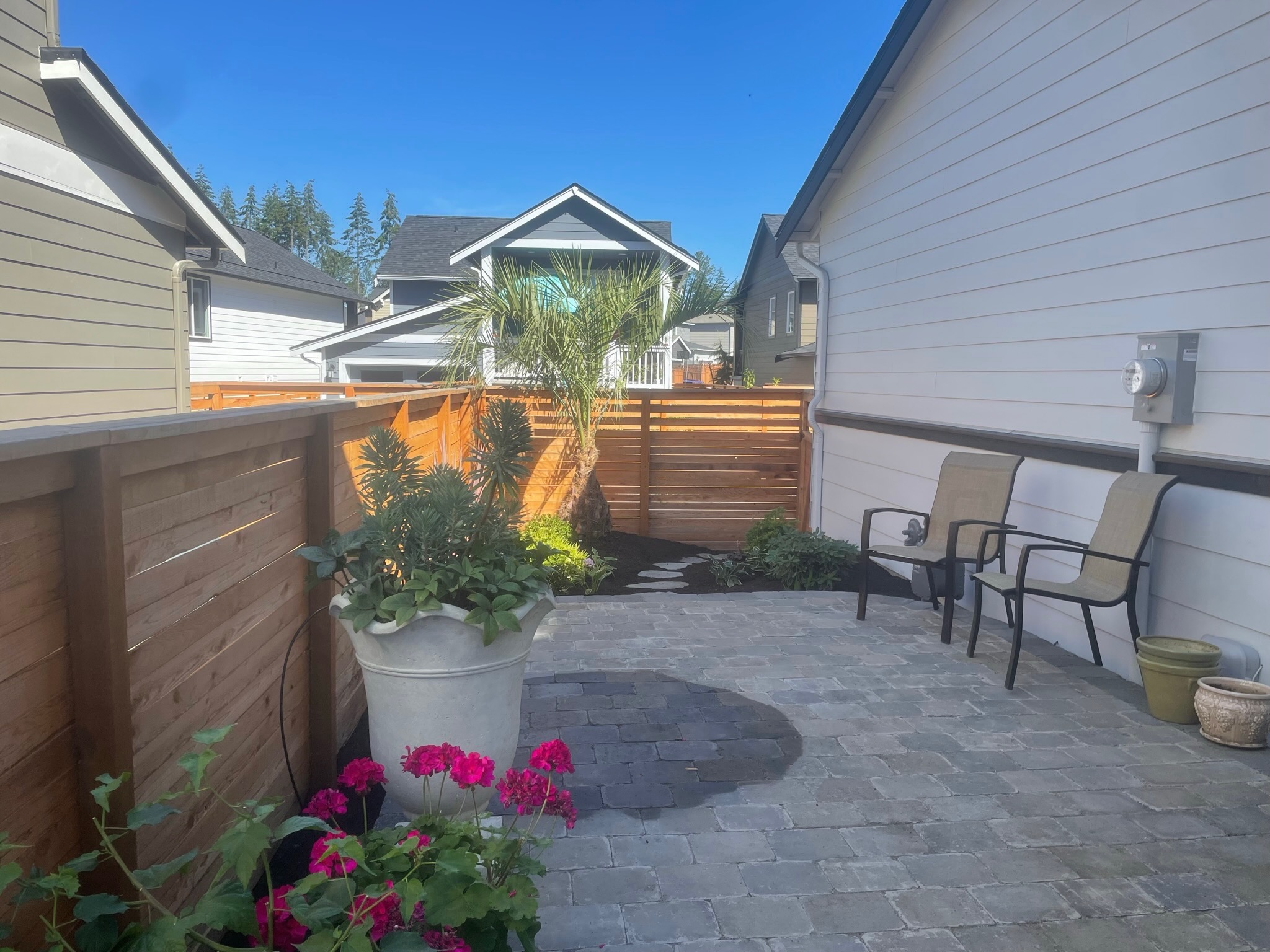 Patio with pavers, tropical plants, and seating by Todd's Nursery in Puyallup, WA