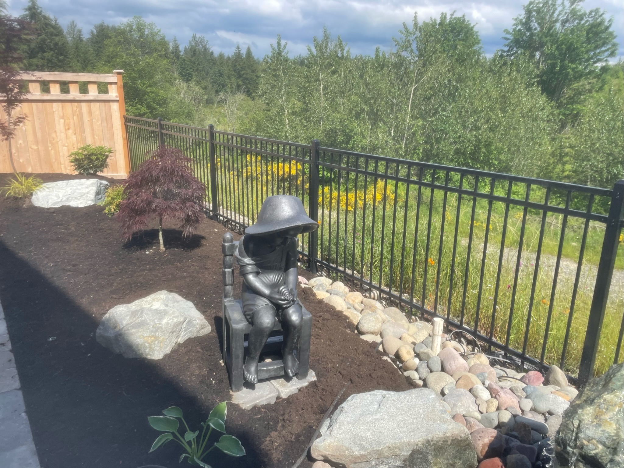 Garden with statue, Japanese maple, rocks, and fence at Todd's Nursery in Puyallup, WA