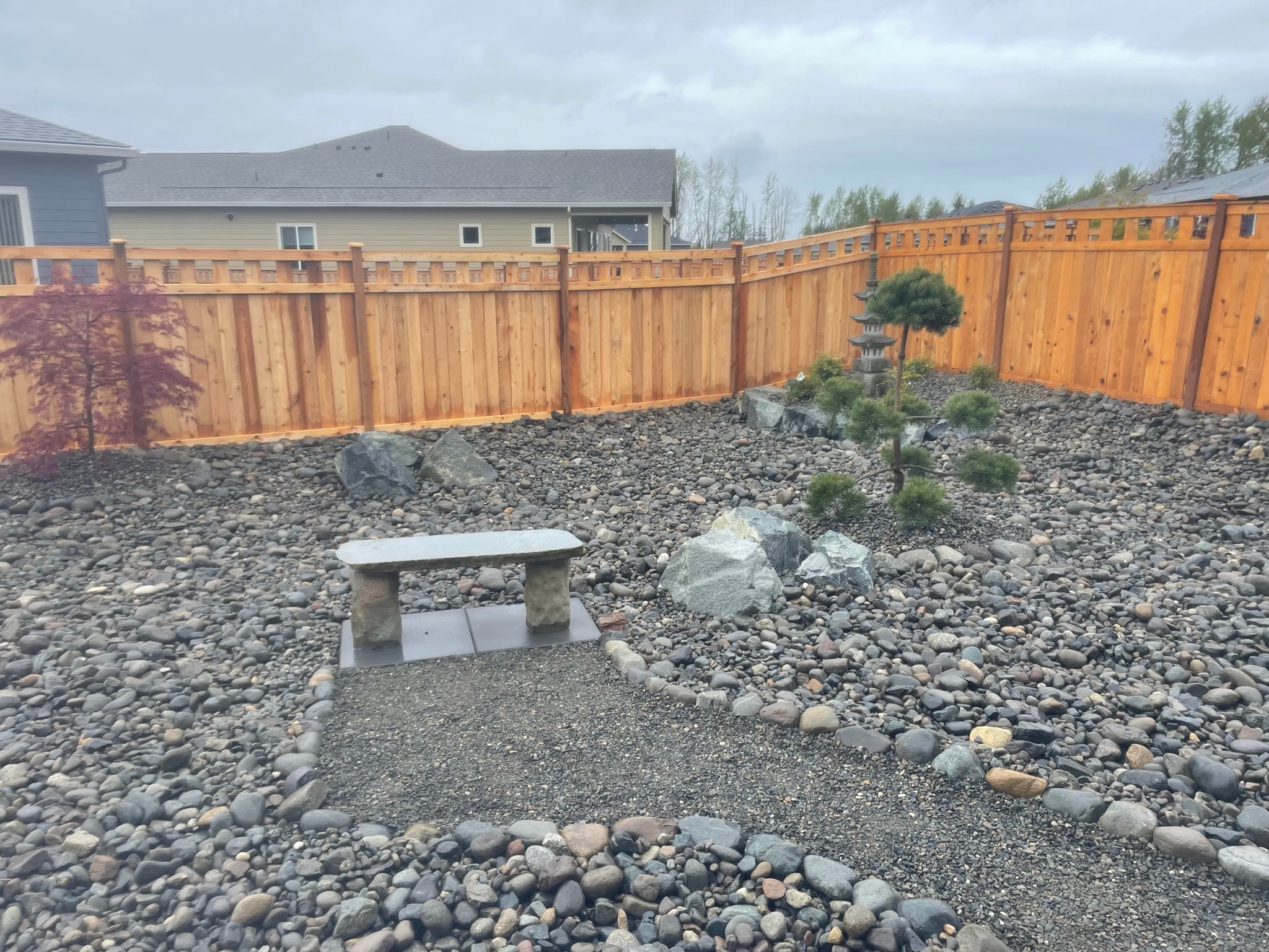 Zen garden with stone bench, pine tree, and rocks by Todd's Nursery in Puyallup, WA