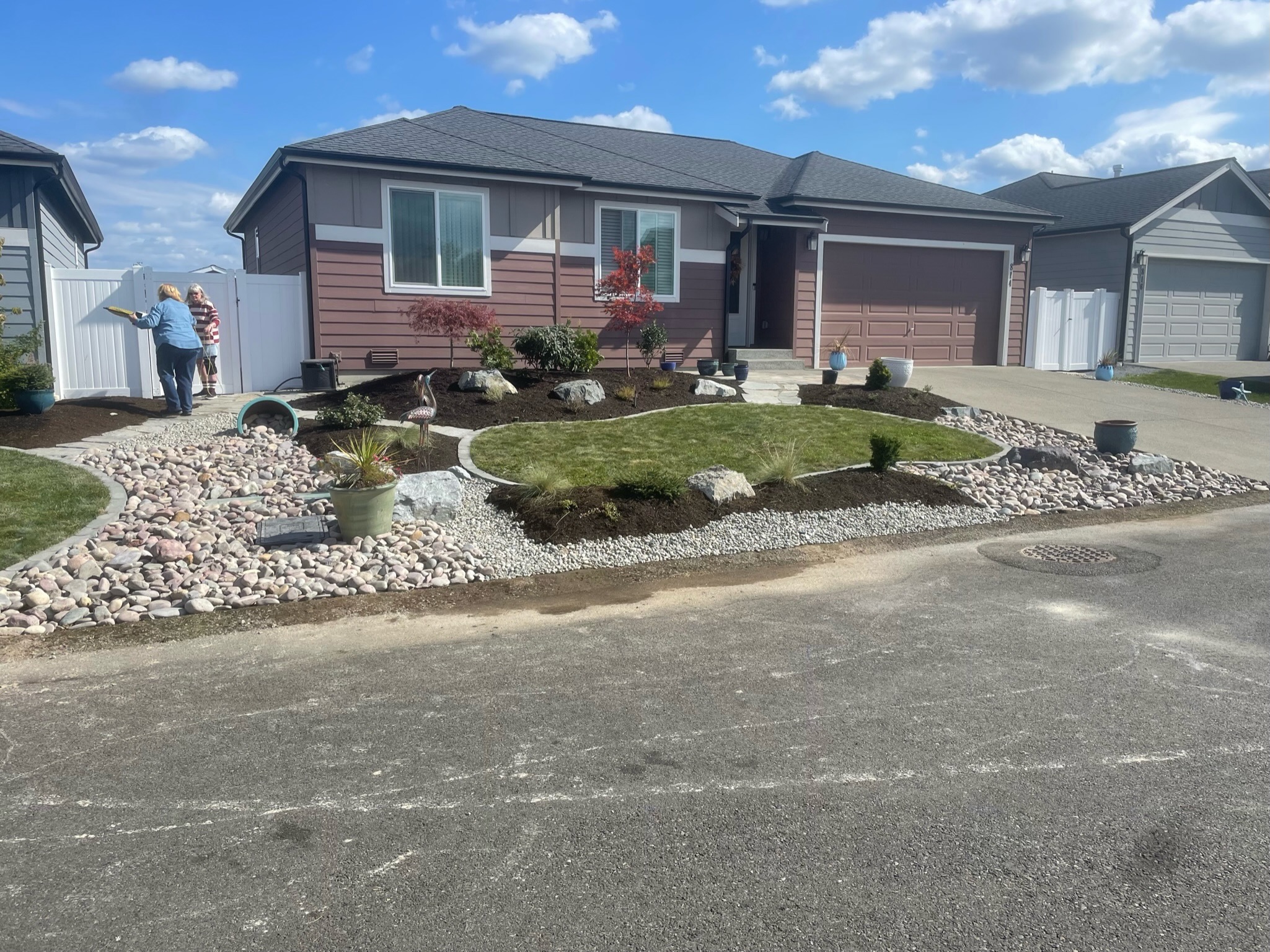 Front yard landscaping by Todd's Nursery in Puyallup, WA featuring rock pathway, shrubs, and decorative pots