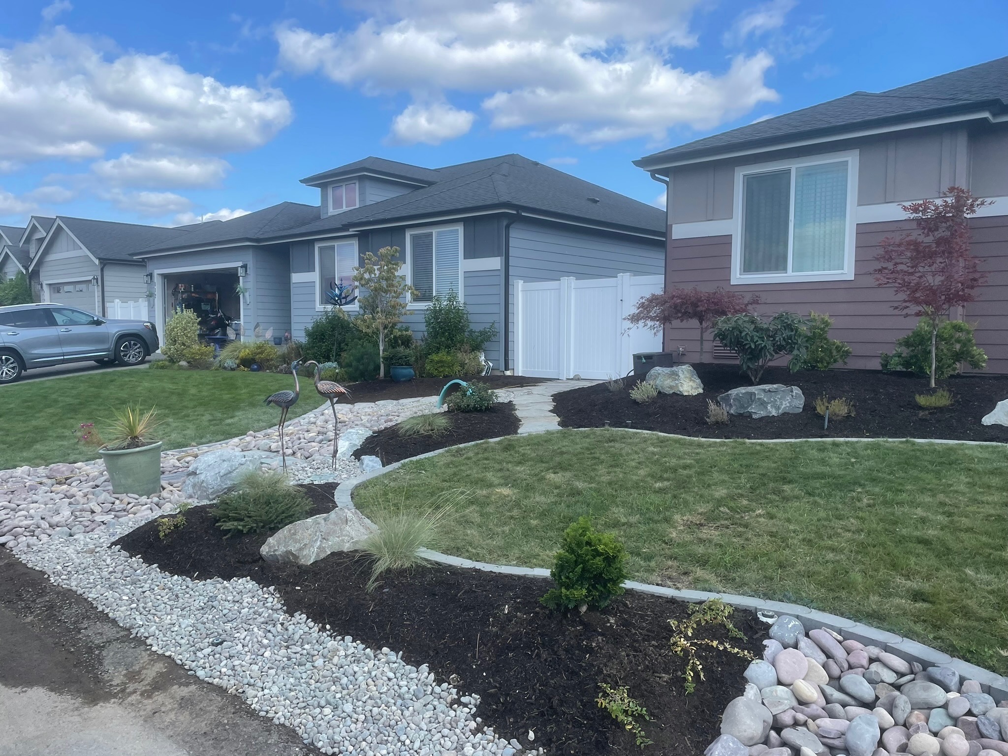 Front yard landscaping by Todd's Nursery in Puyallup, WA featuring pathway, sculptures, and diverse plantings.