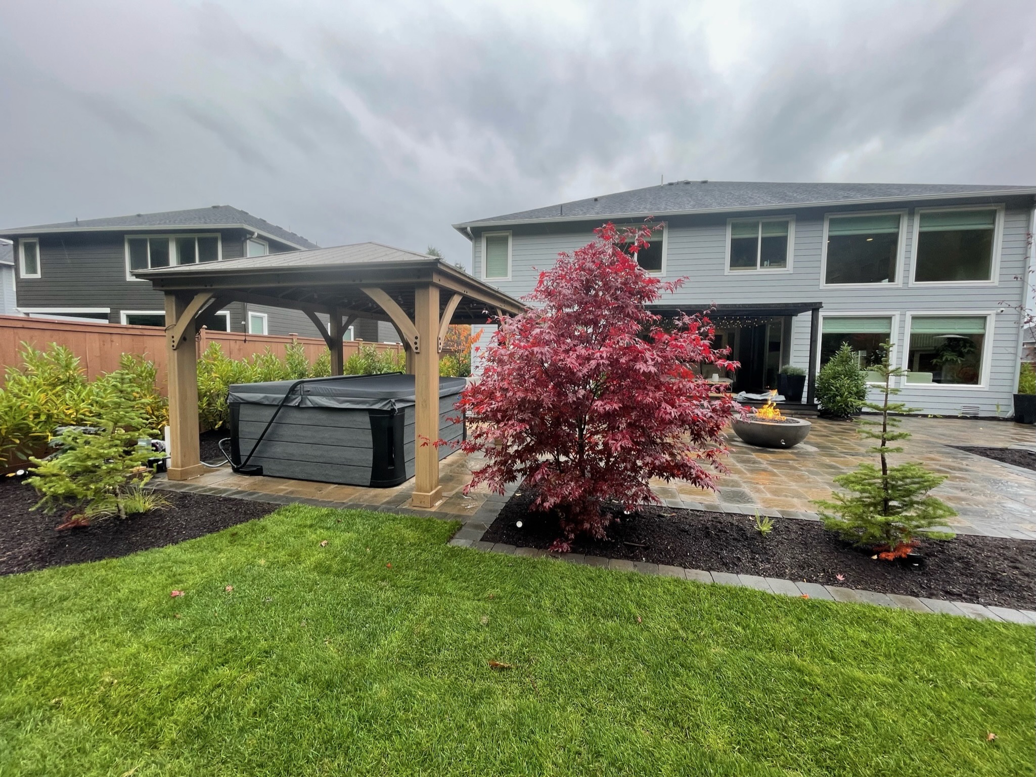 Patio with fire pit, Japanese maple, and hot tub by Todd's Nursery in Puyallup, WA