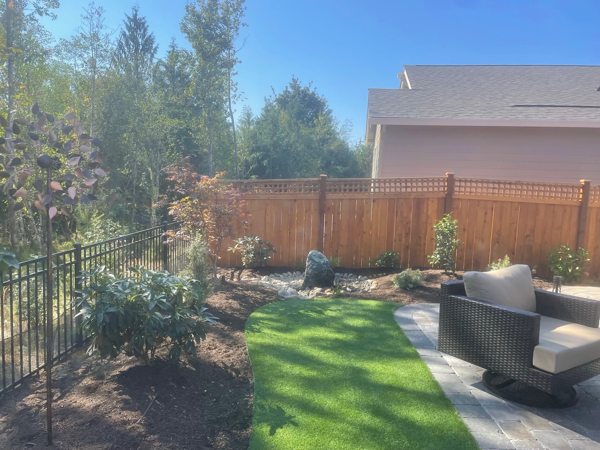 Patio with wicker furniture, lush plantings, and stone path at Todd's Nursery in Puyallup, WA