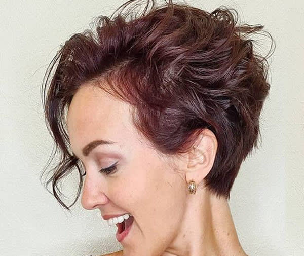 Mulher sorrindo com cabelo curto em corte pixie longo texturizado, topo volumoso e nuca batida.