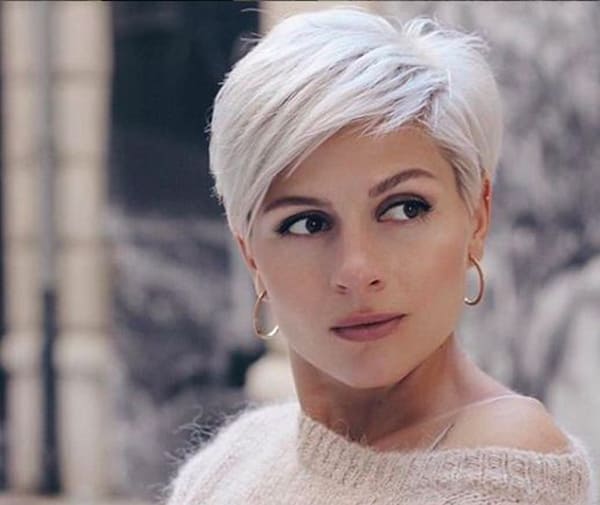 Mulher com cabelo curto em corte pixie platinado, franja lateral longa e visual moderno.