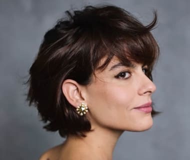 Mulher com corte de cabelo curto bixie texturizado e franja desfiada em vista lateral.