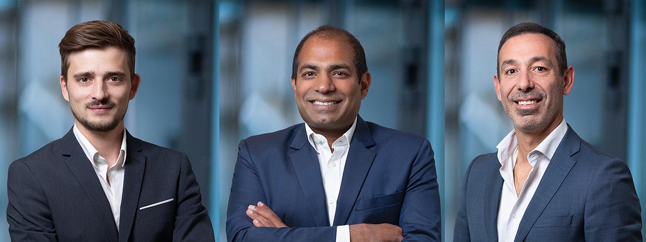photo corporate professionnelle de 3 cadres d'entreprise homme sur un arrière-plan bleu flouté posant pour un photographe à Genève