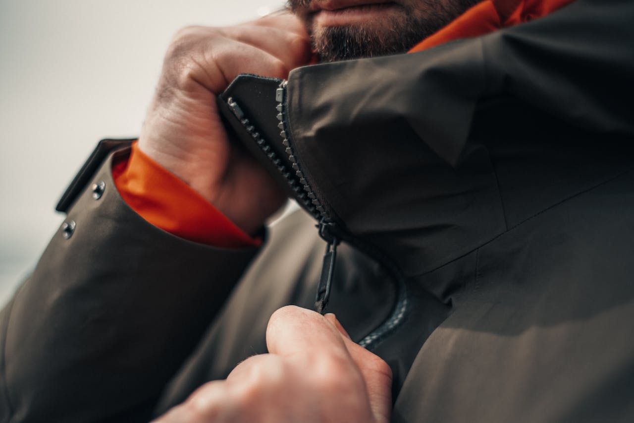 Traveler zipping a lightweight insulated jacket inside an airport boarding lounge