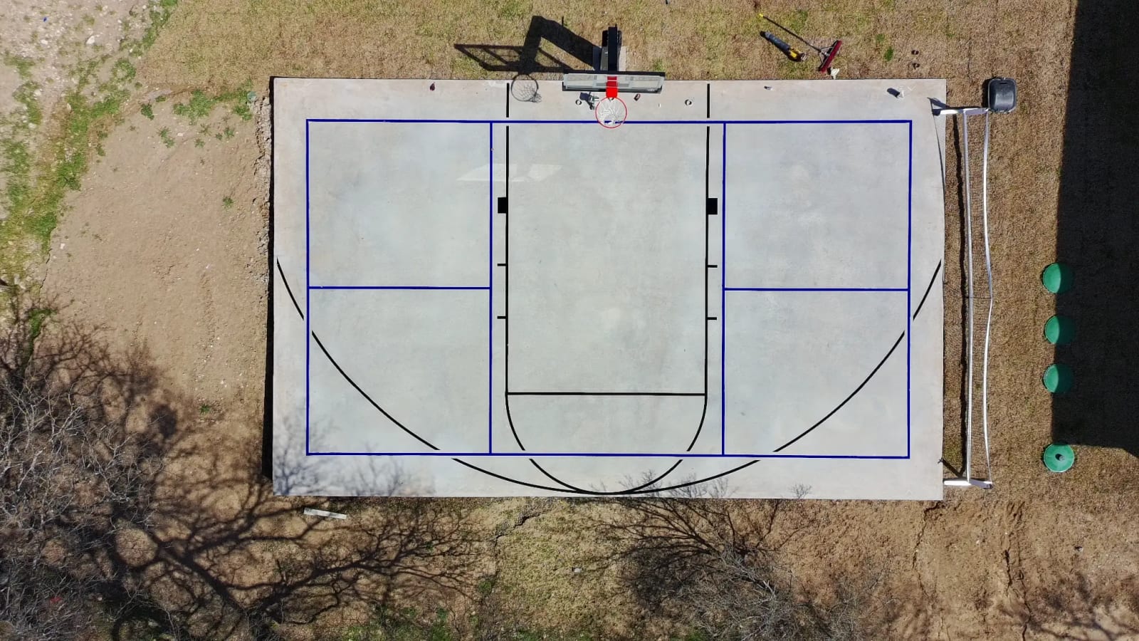 Overhead view of a concrete court slab with a basketball goal and painted court lines