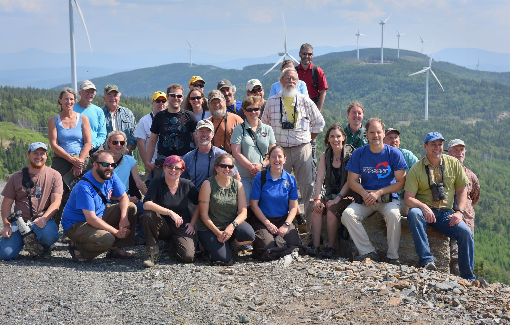 The group is shown during a field trip to a wind farm. Peg standing far left. Tom kneeling center second row. Dr. Todd Katzner stands above all others in the red shirt. Photo by Craig Koppie.