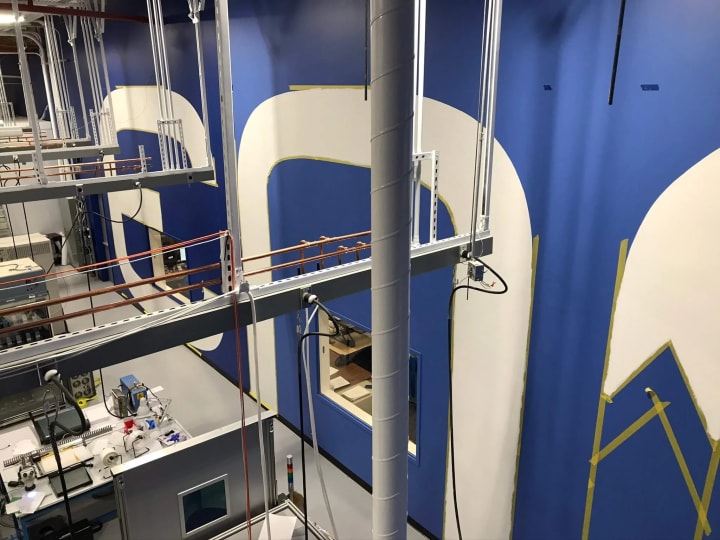 Zoomed-out view from a scissor lift showcases the extensive 30-foot letter installation at a Fremont lithium-ion battery R&D facility, highlighting the project's magnitude and detail