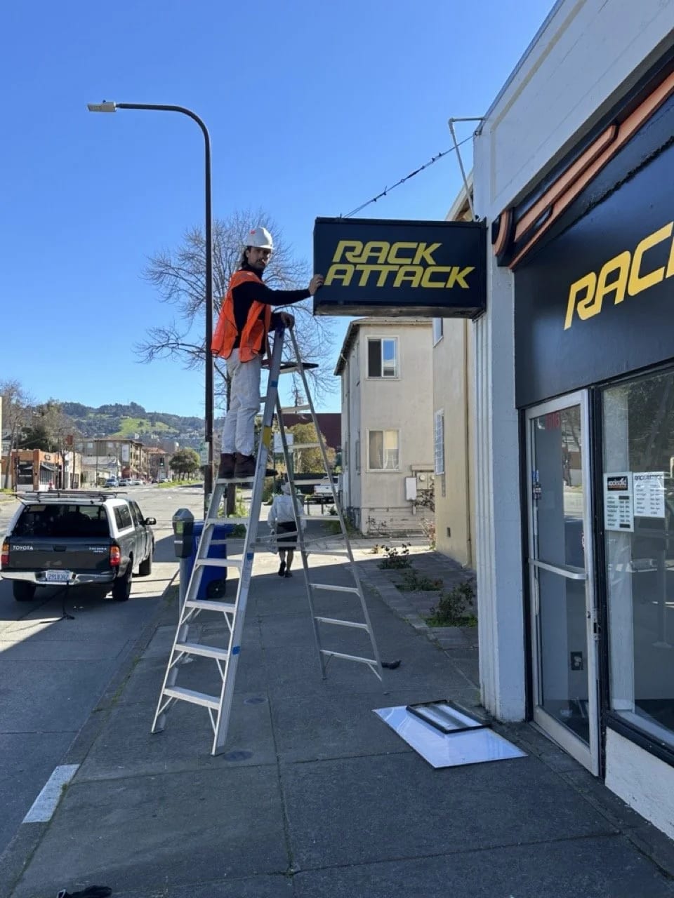 Rack Attack projecting blade sign above the Berkeley storefront, with a ladder at the entrance.