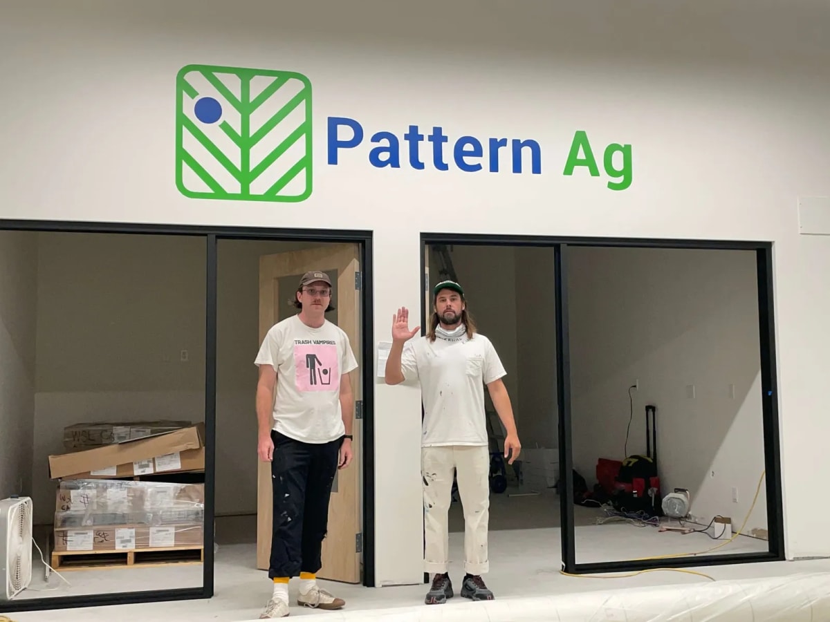 Painters beneath a completed Pattern Ag office logo wall