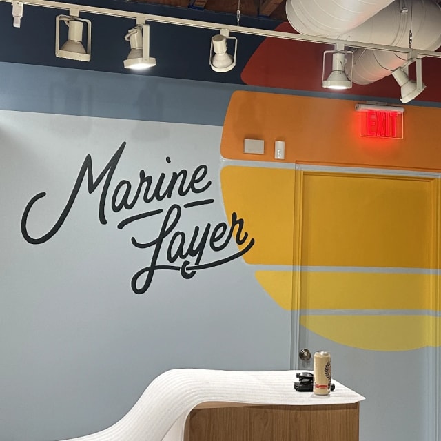 Marine Layer script logo beside a warm-colored striped wall mural for a Sacramento-region client