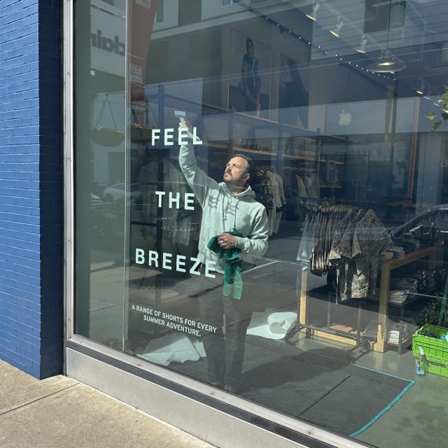 Installer applying Feel the Breeze lettering to a storefront window for a Sacramento business