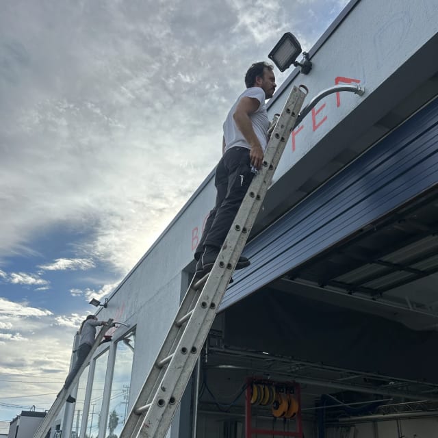 Installer on an extension ladder working above an auto-body shop entrance
