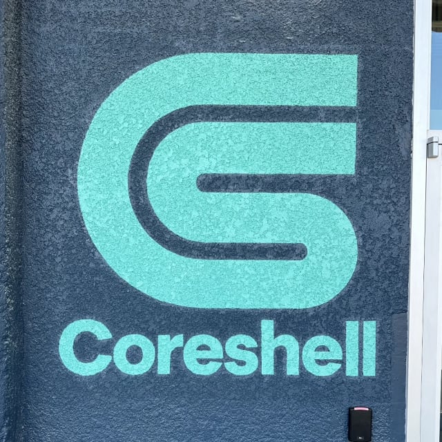 Teal Coreshell logo painted on a dark textured wall