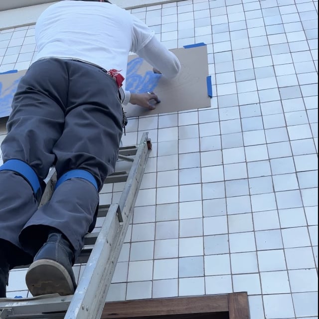 Close-up of an installer applying a sign stencil above a window