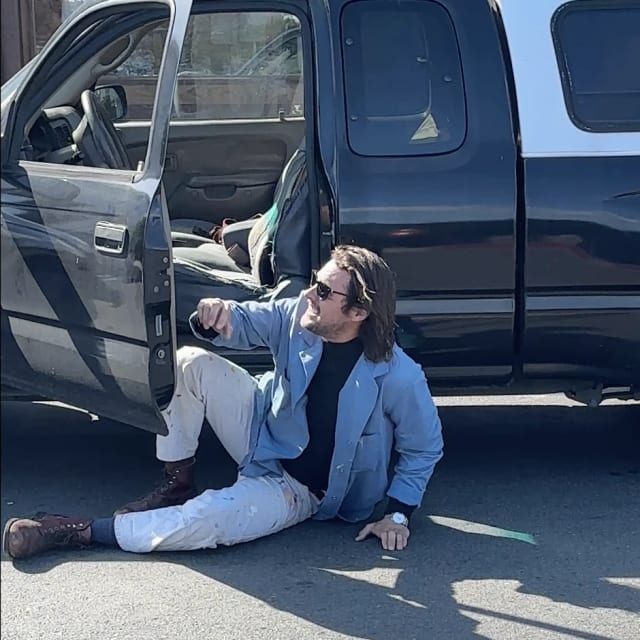 Crew member resting beside an open pickup truck door at a Sacramento sign project