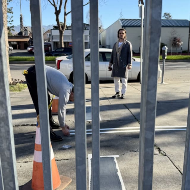 Crew members working beside metal posts and layout marks at a sidewalk