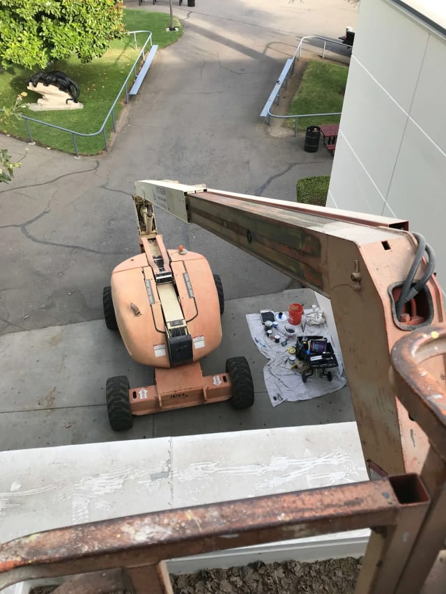 View from an elevated work platform down to a boom lift and parking lot in Sacramento