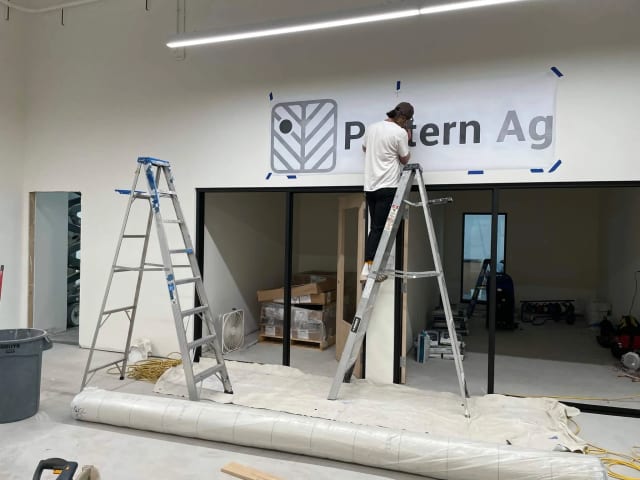 Installer positioning a Pattern Ag logo template above office windows