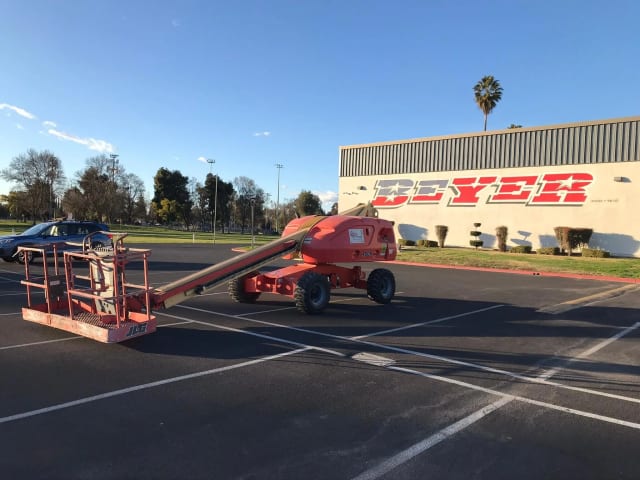 Boom lift parked outside a school building with large Beyer lettering in Sacramento