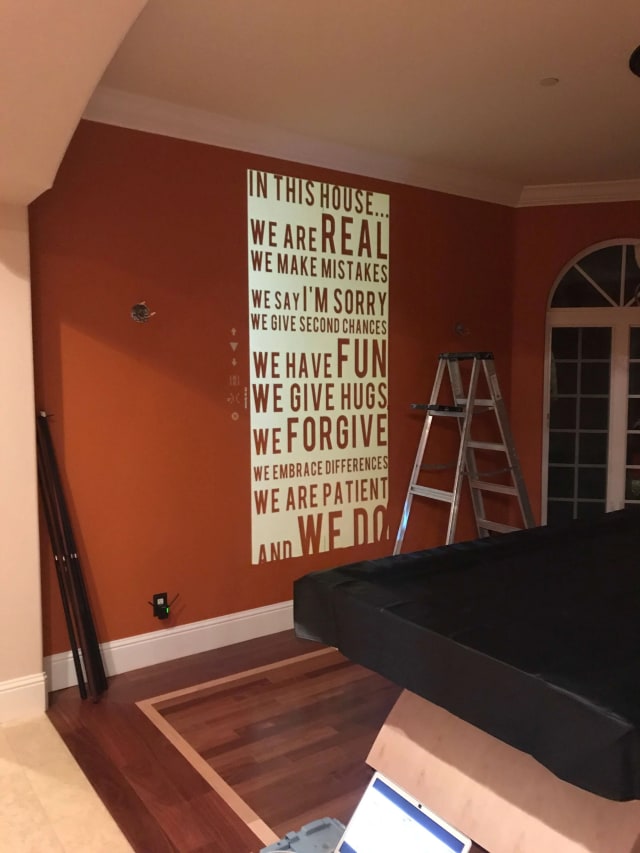 Tall white word mural on a red dining-room wall