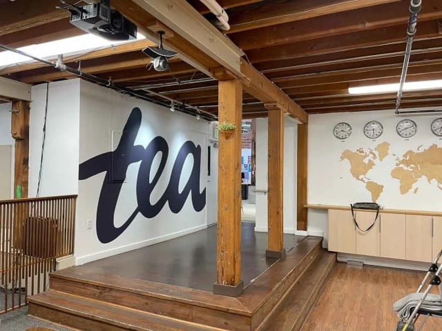 Large tea script logo on an office wall beside exposed wood posts