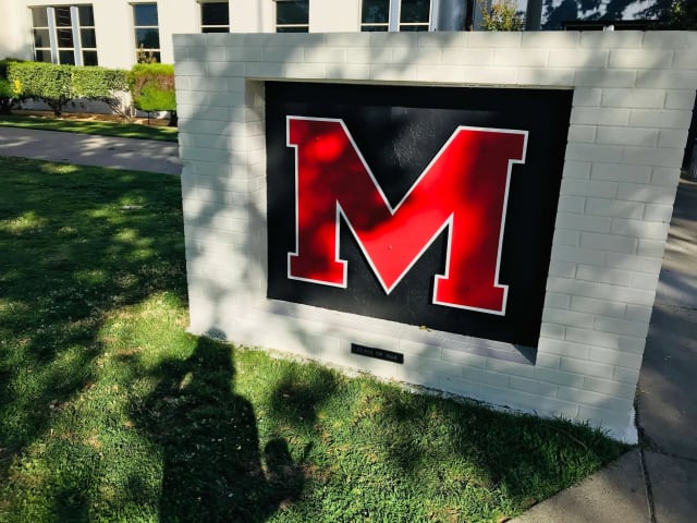 Red dimensional M logo inset in a low courtyard wall