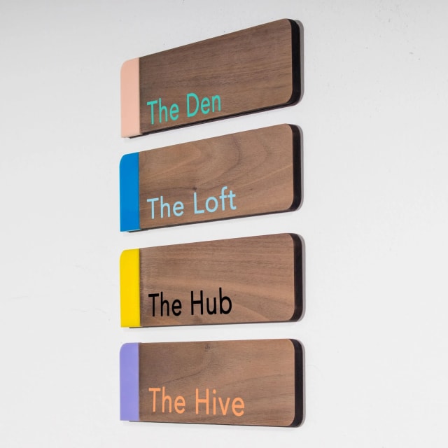 Four wooden room signs labeled The Den, The Loft, The Hub and The Hive for Sacramento offices