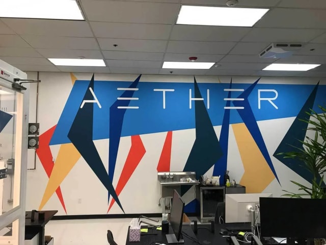 Aether lettering above a colorful geometric office mural