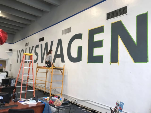 Large Volkswagen wall lettering with ladders and scaffolding set up below at a Sacramento auto dealership