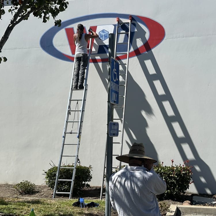 Exterior Wall Logo Sign Installation On Ladder.