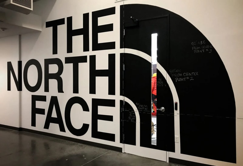 Large hand-painted North Face logo wall inside an Alameda corporate workspace