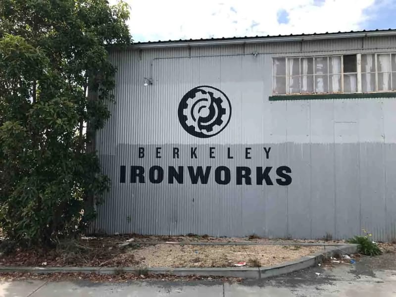 Wide exterior view of the Berkeley Ironworks warehouse logo mural