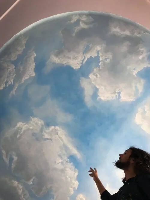 Muralist showing a hand-painted cloud ceiling detail