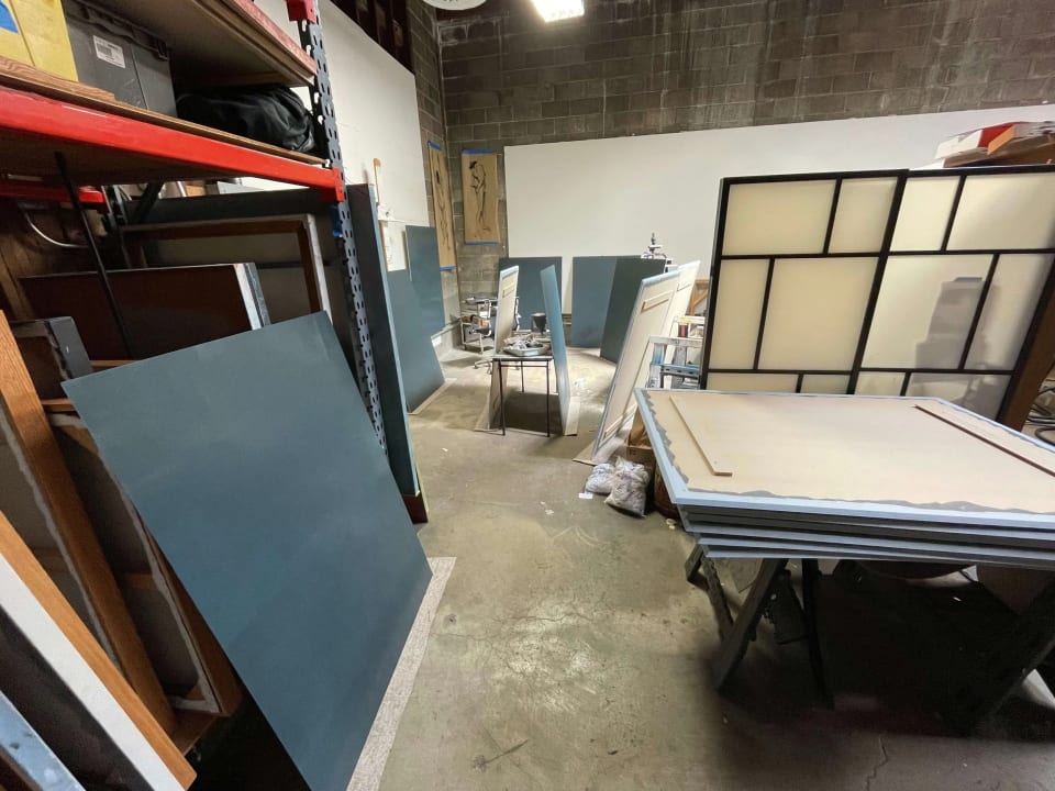 Blue-gray painted sign panels and framed sections staged in a workshop.
