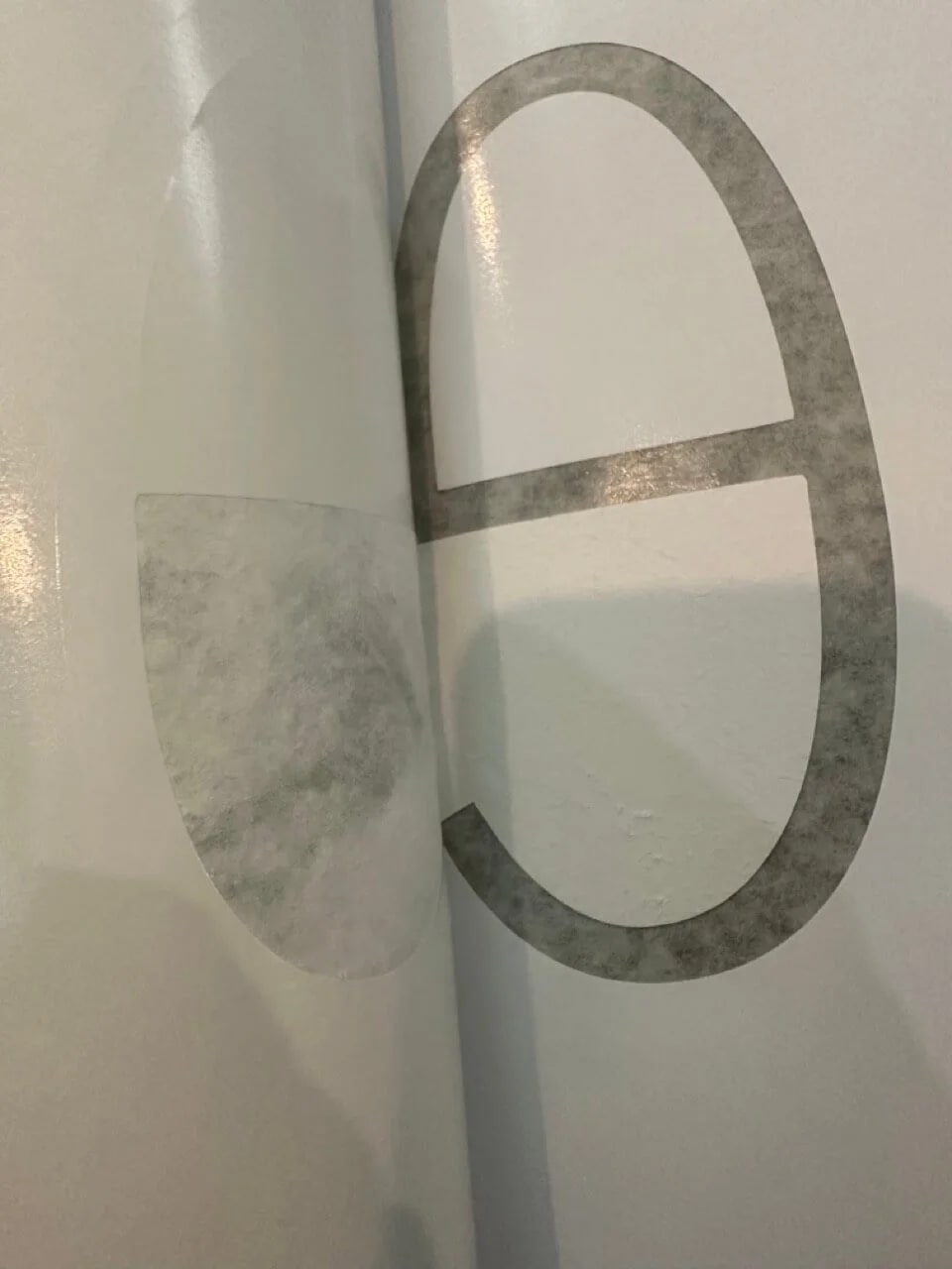 Close-up of cut translucent vinyl being aligned on a smooth sign surface.