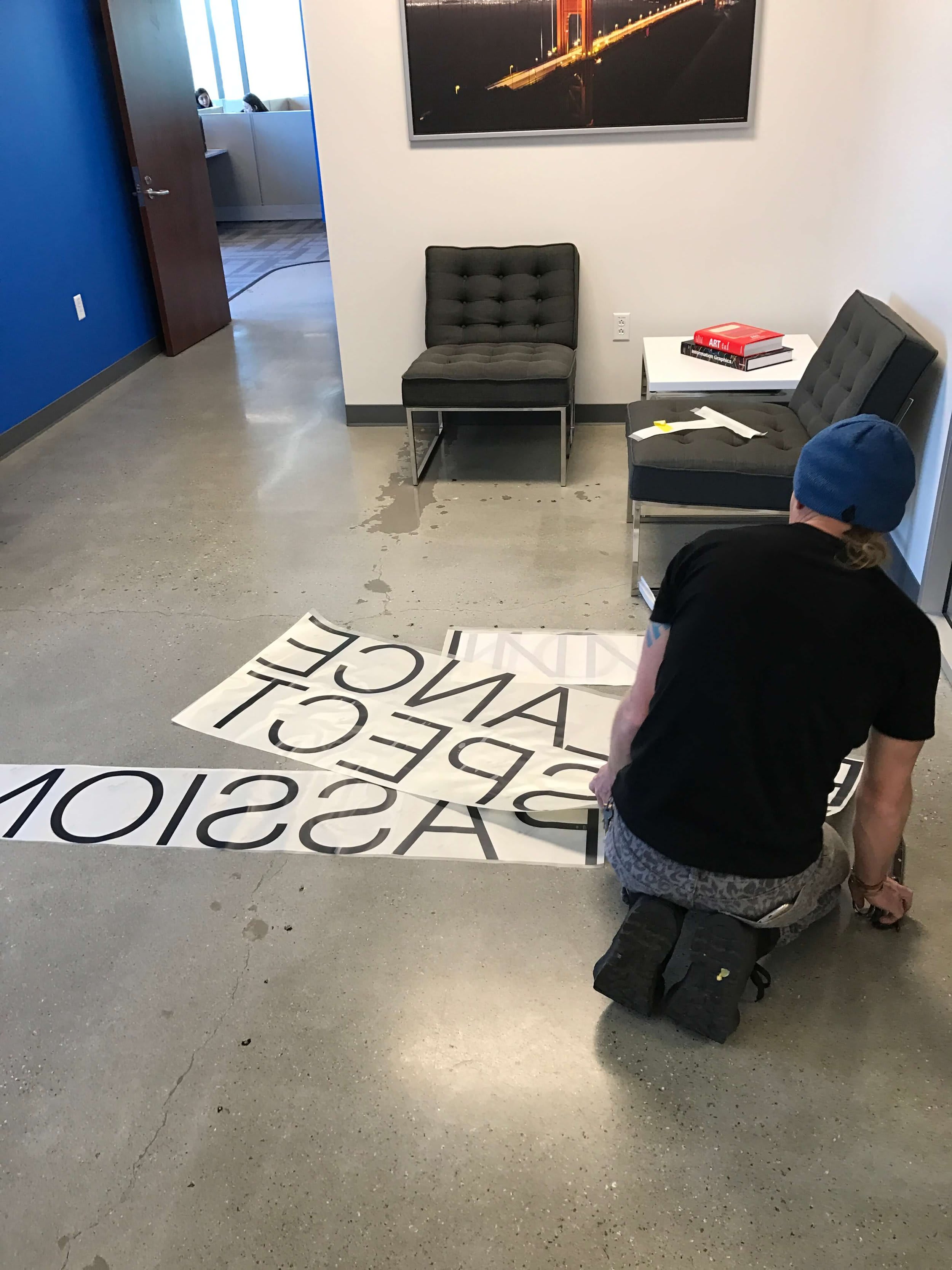 Installer positioning black vinyl lettering on an office wall