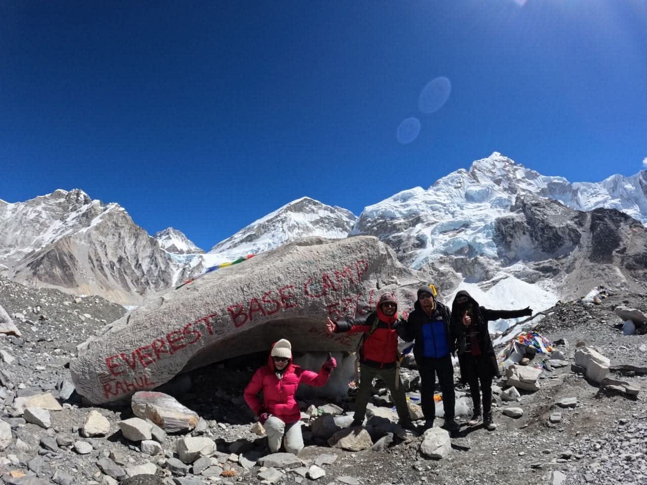 Mount Everest Base Camp sign draped in Buddhist prayer flags with snow peaks in the background