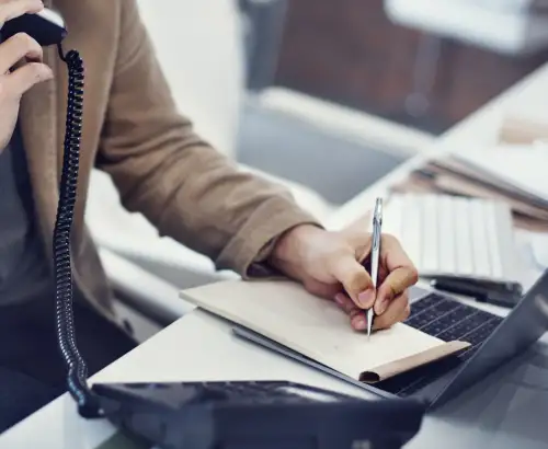 Main qui prend des notes près d'un téléphone