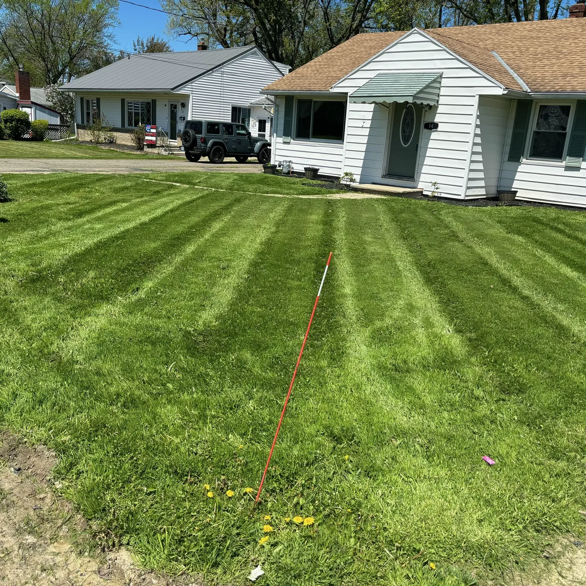 A beautiful dark and light striped lawn in front of a house, showcasing the artistry of our lawn care